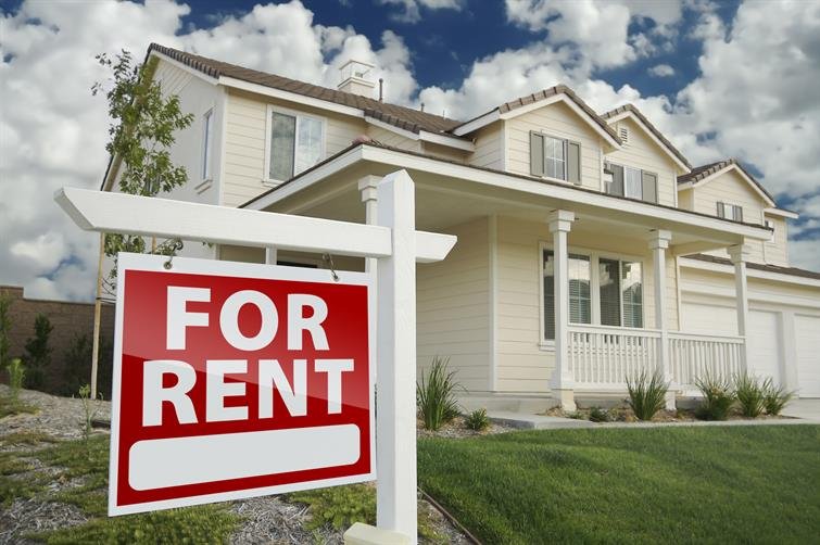 A house with a front porch and a red For Rent sign